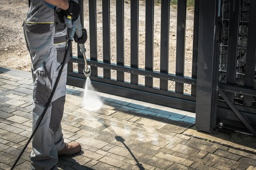 A male worker spraying the gate entrance.