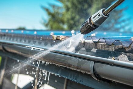 A picture of a house gutter being pressure washed.