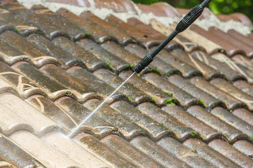 Spraying down the top of a roof with a pressure washer.