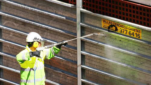 Worker cleaning graffiti off a wall.